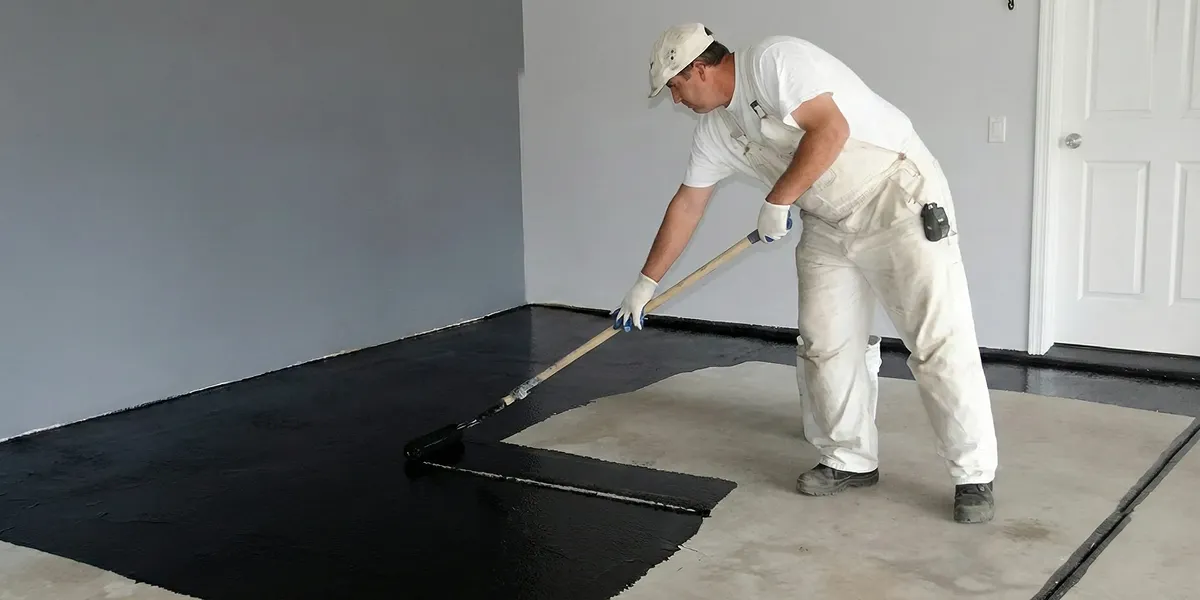 basement waterproofing professional applying waterproof coating to protect a basement floor in Bloomington, IN